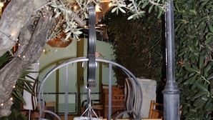 Een binnenplaats met een metalen lantaarnpaal, rieten meubilair en potplanten.