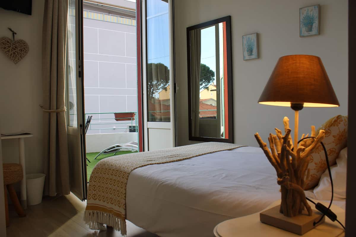Une chambre à coucher avec un lit, une lampe de chevet, une fenêtre avec des rideaux et une vue sur l’extérieur.