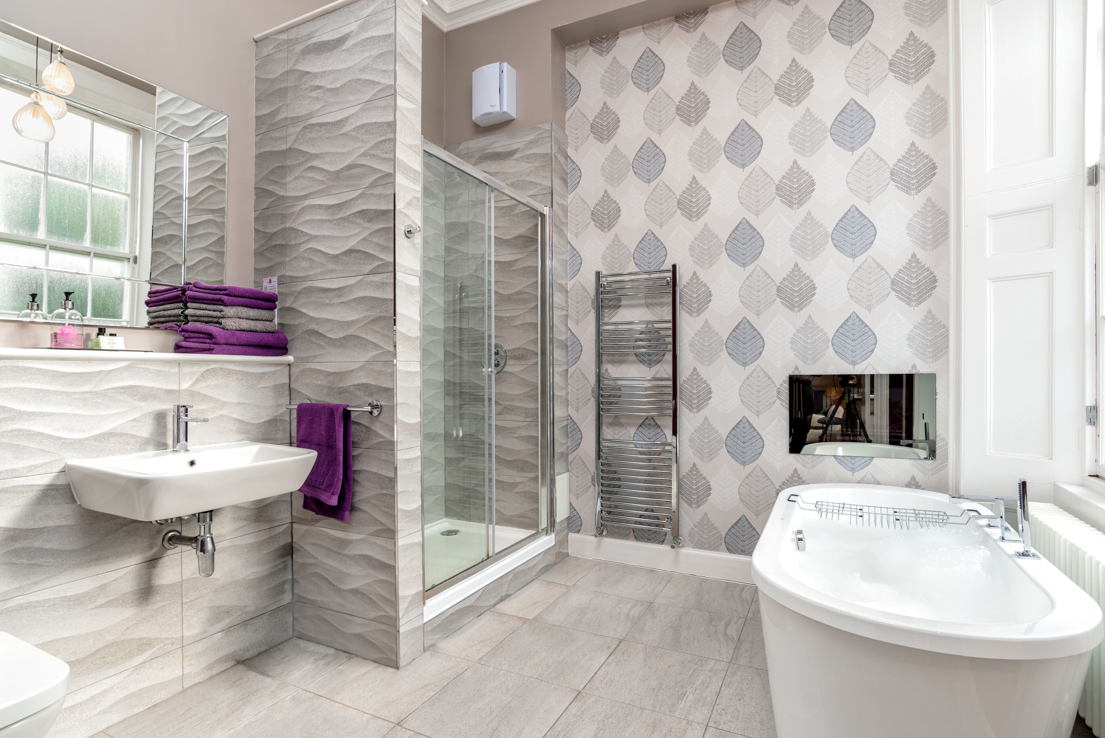 A modern bathroom with a glass-enclosed shower, a freestanding bathtub, and a vanity with a sink and mirror.