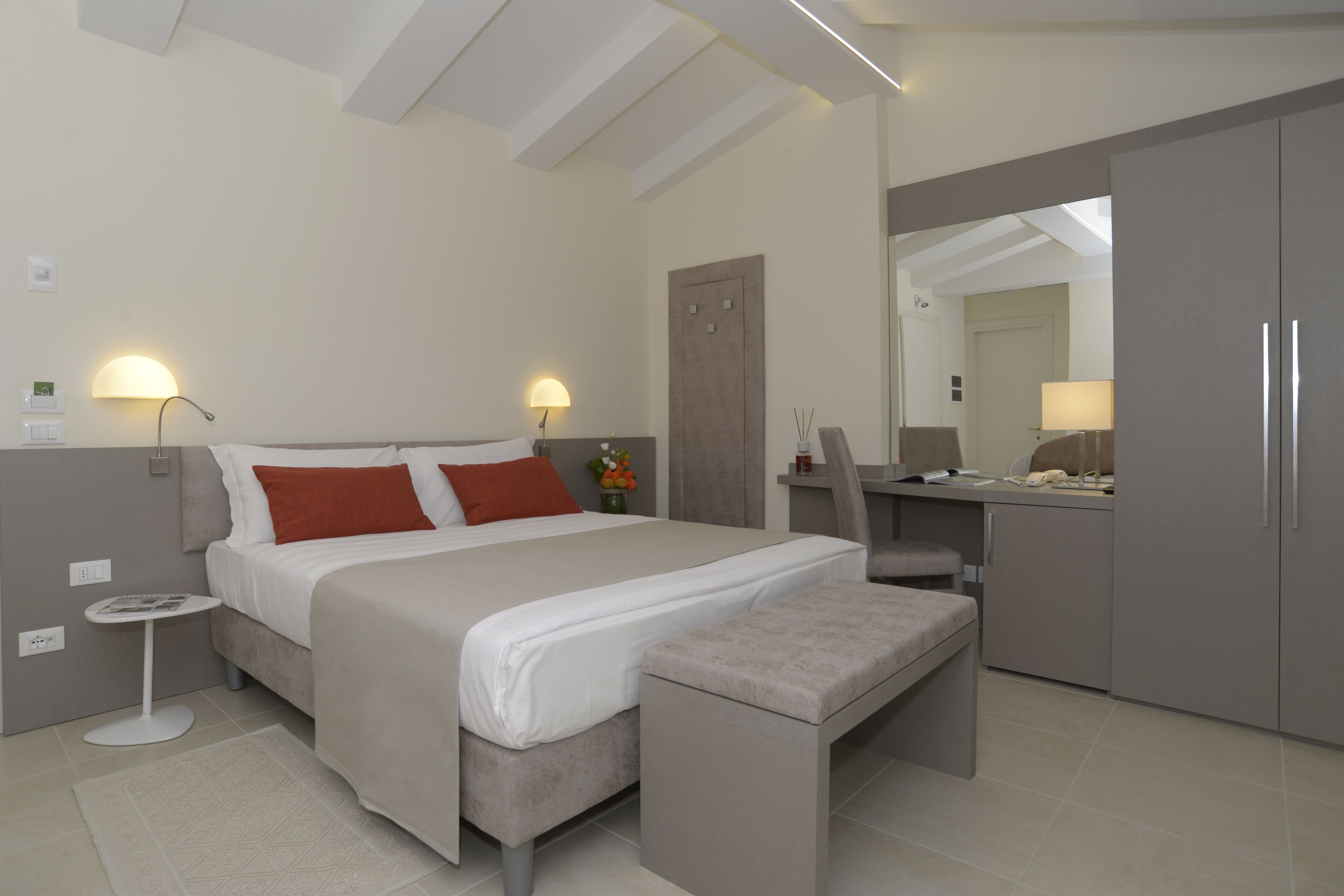 A modern bedroom with a bed, bedside tables, a desk, and a wardrobe.