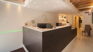 A hotel reception area with a modern design, featuring a reception desk, a wall-mounted sign, and a wooden ceiling. - Hotel Leone (Venice)
