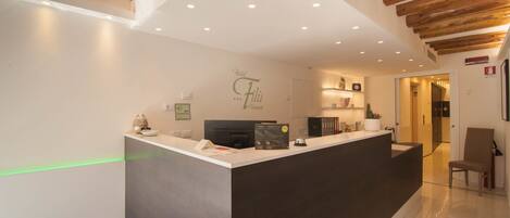 A hotel reception area with a modern design, featuring a reception desk, a wall-mounted sign, and a wooden ceiling.