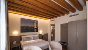 A bedroom with a bed, bedside tables, a nightstand, a wardrobe, and a painting of a lighthouse. - Hotel Leone (Venice)