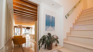A modern interior with a staircase, a potted plant, and a painting on the wall. - Hotel Leone (Venice)