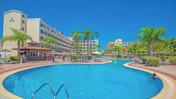 A hotel with a large swimming pool, palm trees, and multiple buildings. - Tsokkos Gardens (Paralimni)