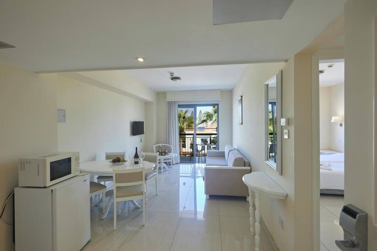 A modern, well-lit room with a dining area, a sofa, and a bed.