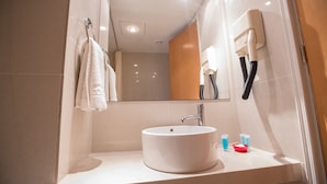 A modern bathroom with a white sink, a mirror, and a towel rack.