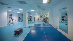 A gym with exercise equipment, a blue floor, and mirrors on the walls.