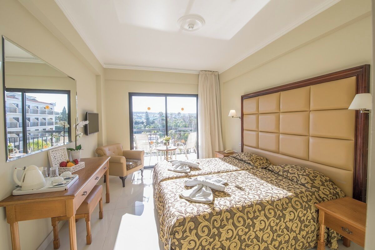 Ein Hotelzimmer mit einem großen Bett, einem Schreibtisch mit Stuhl, einem Fernseher und einem Balkon mit Aussicht.
