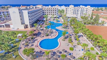 Ein Hotel mit Poolbereich, mehreren Stockwerken und Meerblick.
