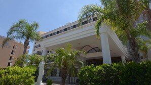 A multi-story hotel with a central atrium, palm trees, and a statue in the foreground.