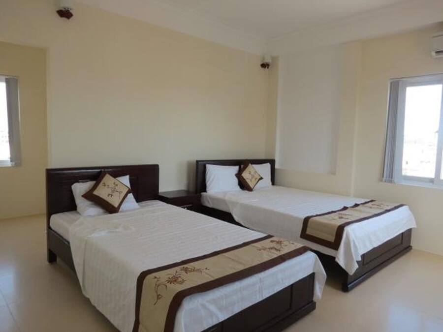 A hotel room with two single beds, each with a wooden headboard and a white bedspread.