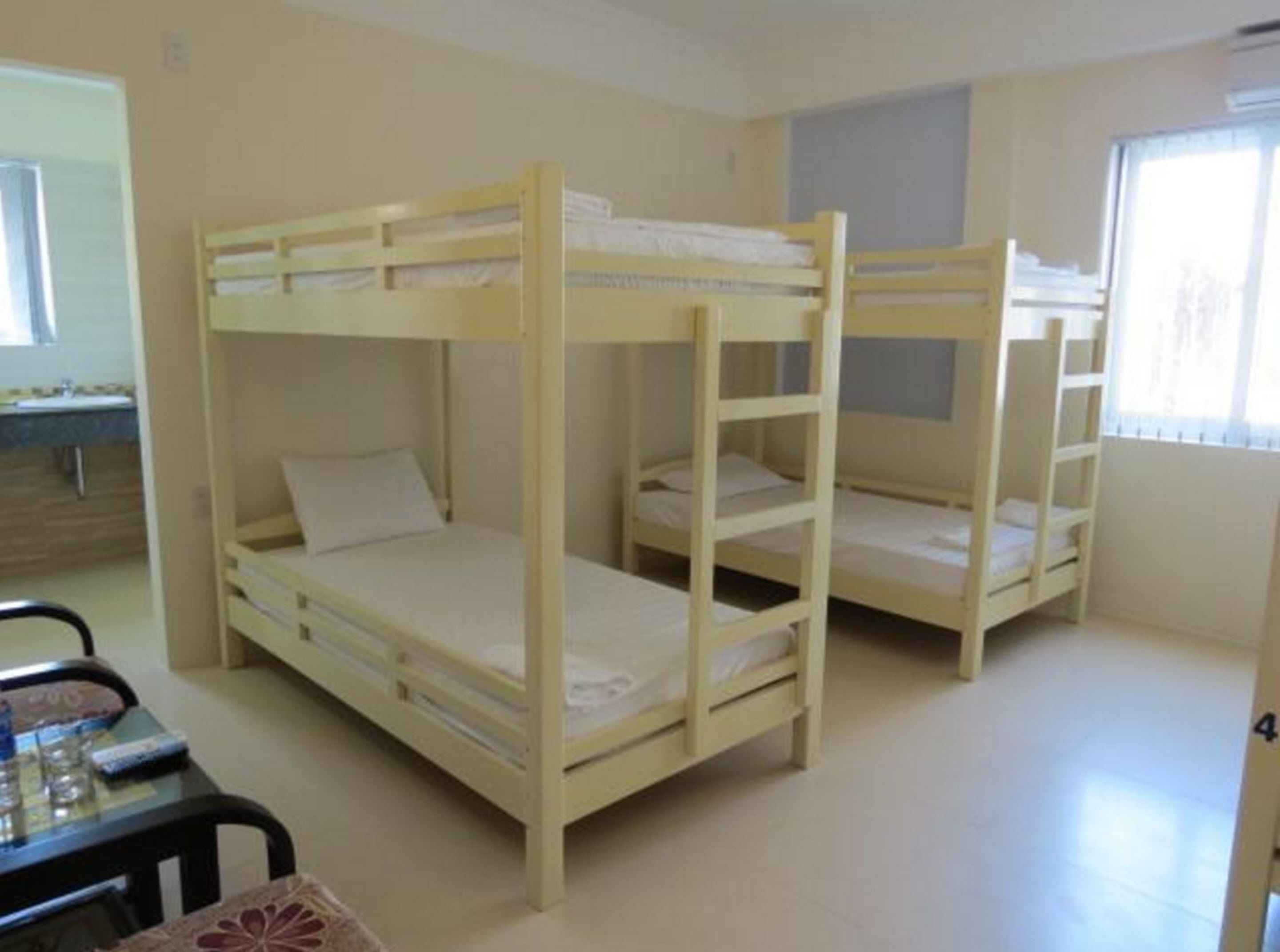 Une chambre avec des lits superposés, une petite table et une fenêtre.