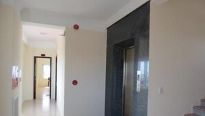 A hallway with a marble wall and a door, leading to a staircase. - Nam Long Plus Hotel (Dong Hoi)
