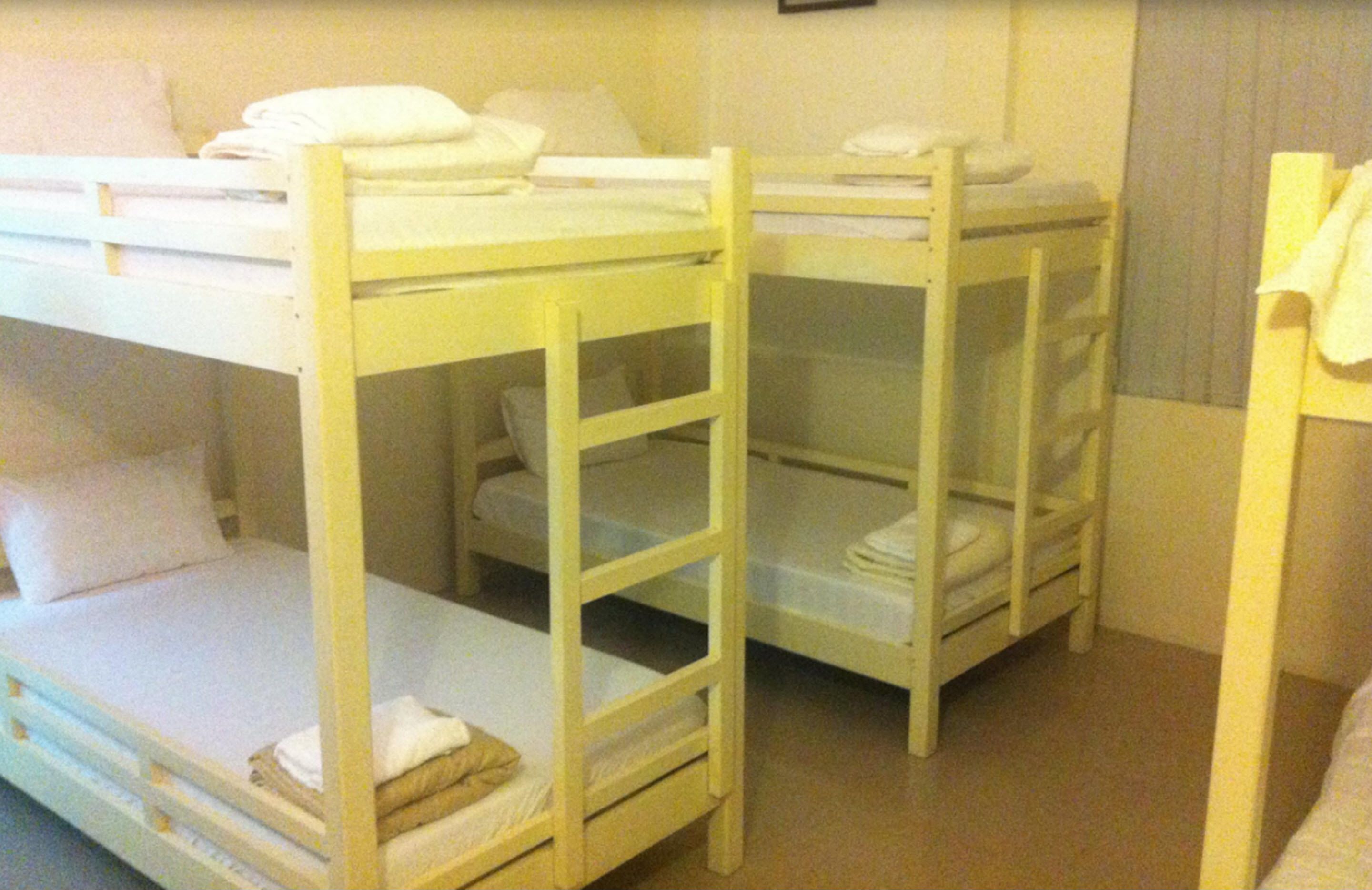 A room with bunk beds, each with a ladder, and a small table with a chair.
