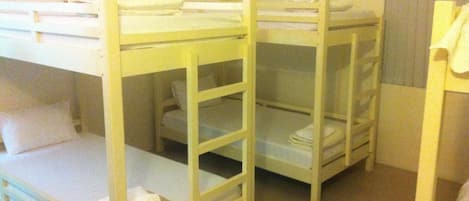 Una habitación con literas, cada una con una escalera, y una pequeña mesa con una silla.