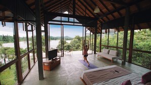 A spacious room with large windows offering a view of a river and forest. - Wild Grass Nature Resort (Dambulla)