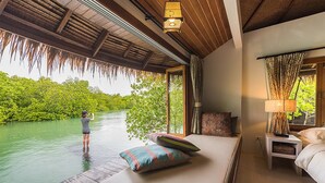 Un dormitorio con vista al río, techo de madera y mesita de noche con lámpara.