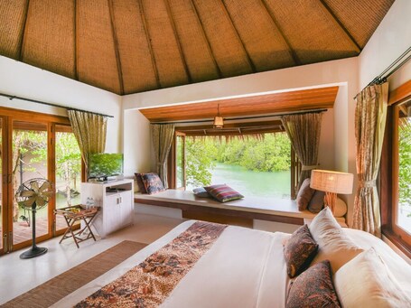 A bedroom with a large bed, a desk, and a view of a lake.