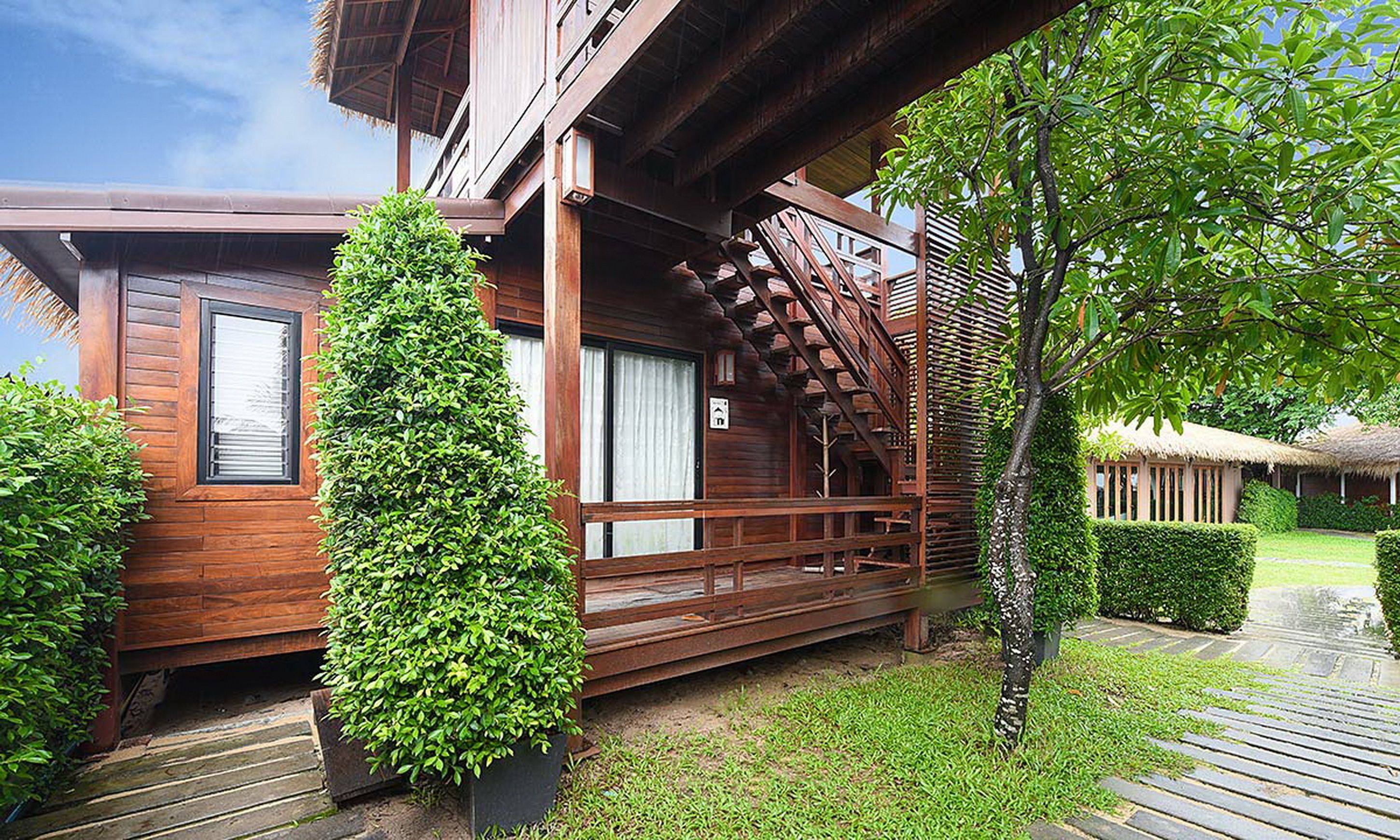 Une cabane en bois dotée d’un balcon, d’un escalier et d’un jardin bien entretenu.