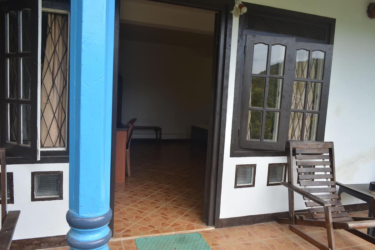 A room with a tiled floor, a wooden chair, a table, and a window with a metal grille.