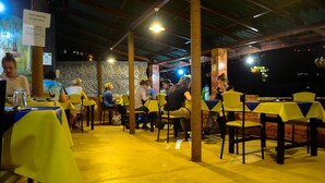 An indoor dining area with yellow tablecloths and wooden pillars. - Rawana Holiday Resort (Ella)
