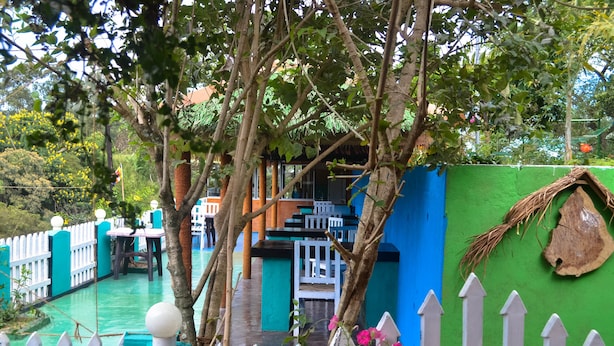 A courtyard with a pool, a white picket fence, and a blue wall. - Rawana Holiday Resort (Ella)