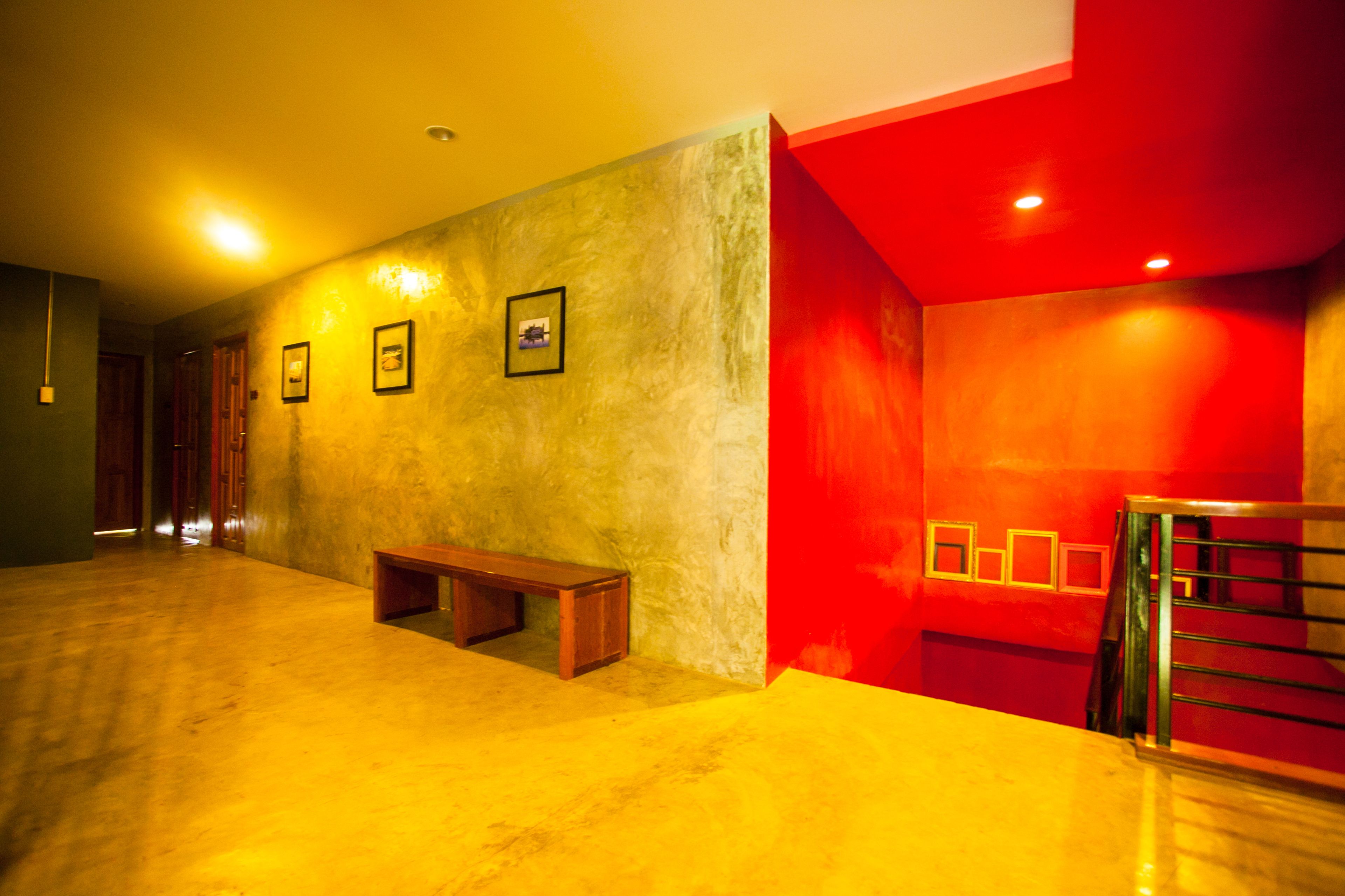A hallway with a wooden bench, a staircase with metal railings, and framed pictures on the wall.