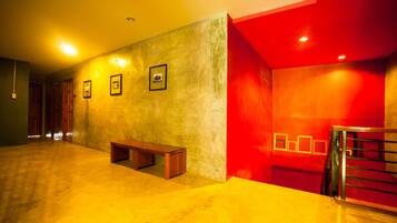 A hallway with a wooden bench, a staircase with metal railings, and framed pictures on the wall.