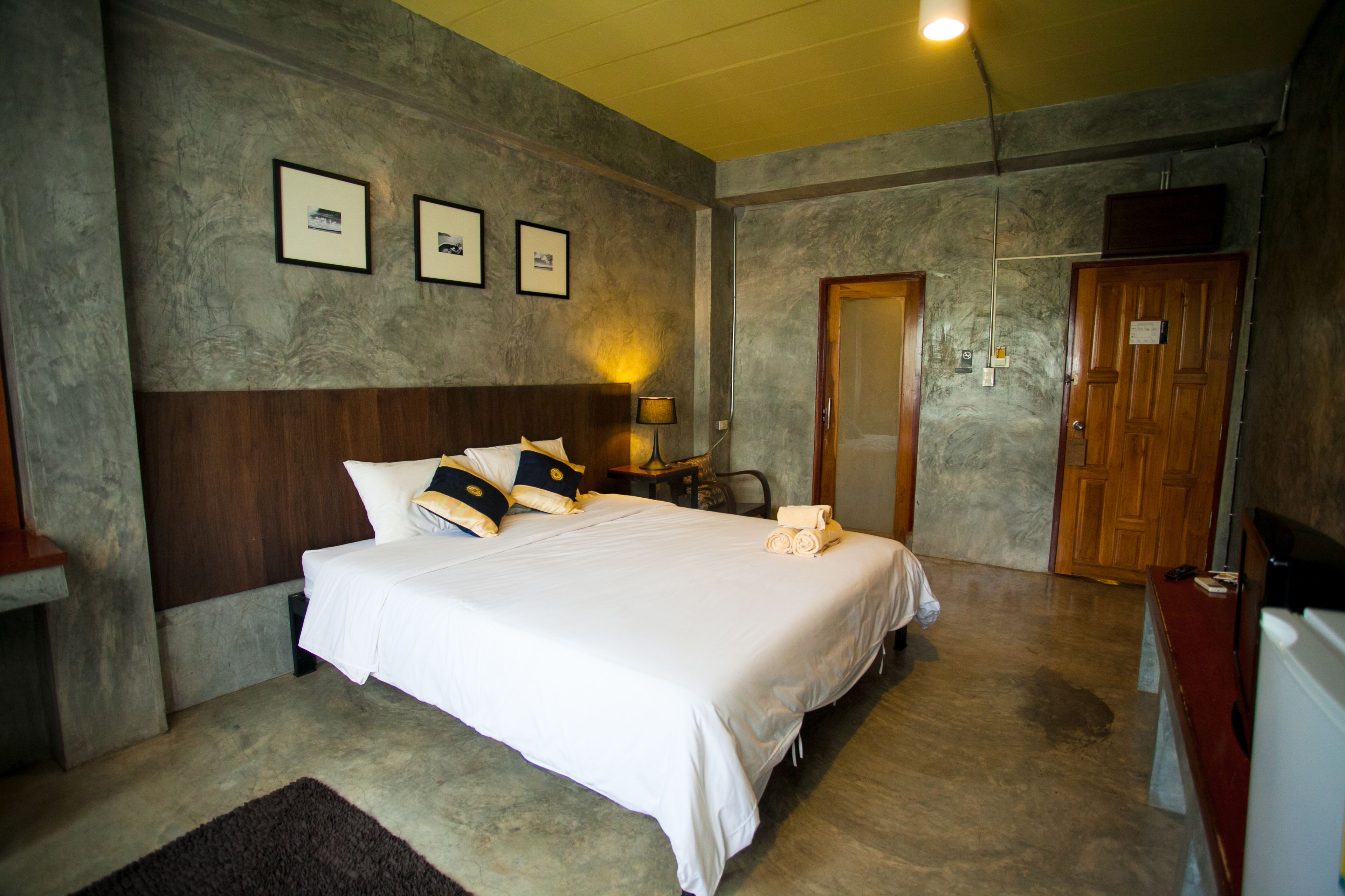 A hotel room with a large bed, a wooden headboard, a desk, a chair, and a door.