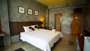 A hotel room with a large bed, a wooden headboard, a desk, a chair, and a door.