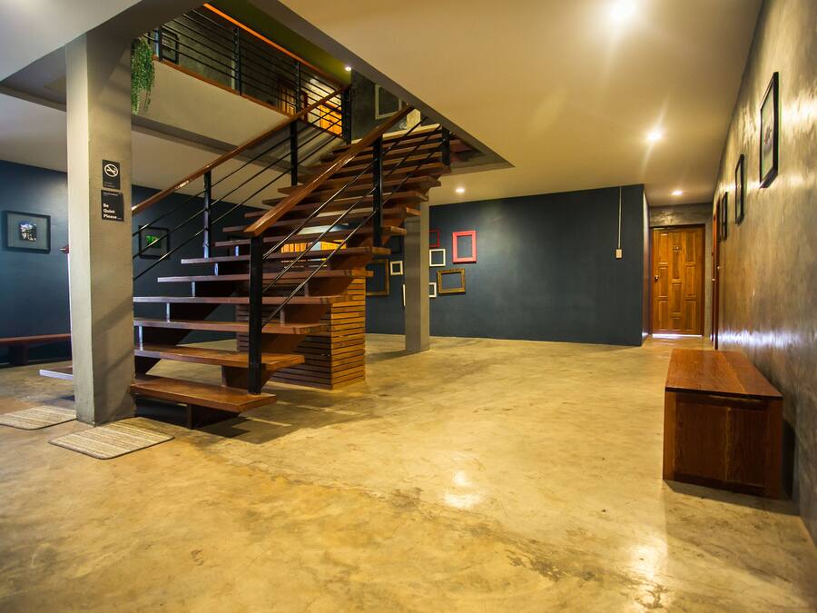 A spacious interior with a wooden staircase, a concrete floor, and a wooden bench.