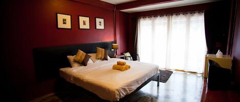 Habitación de hotel con una cama grande, un escritorio y una ventana con cortinas.