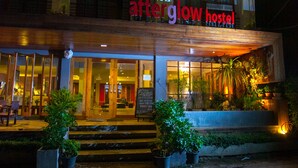 Un hostal con un letrero que dice "afterglow hostel" y una entrada bien iluminada con macetas.
