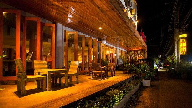 Un restaurante con terraza, mesas y sillas de madera, y un camino de ladrillo.
