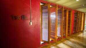 Un pasillo con paredes rojas, separadores de madera y techo con iluminación empotrada.