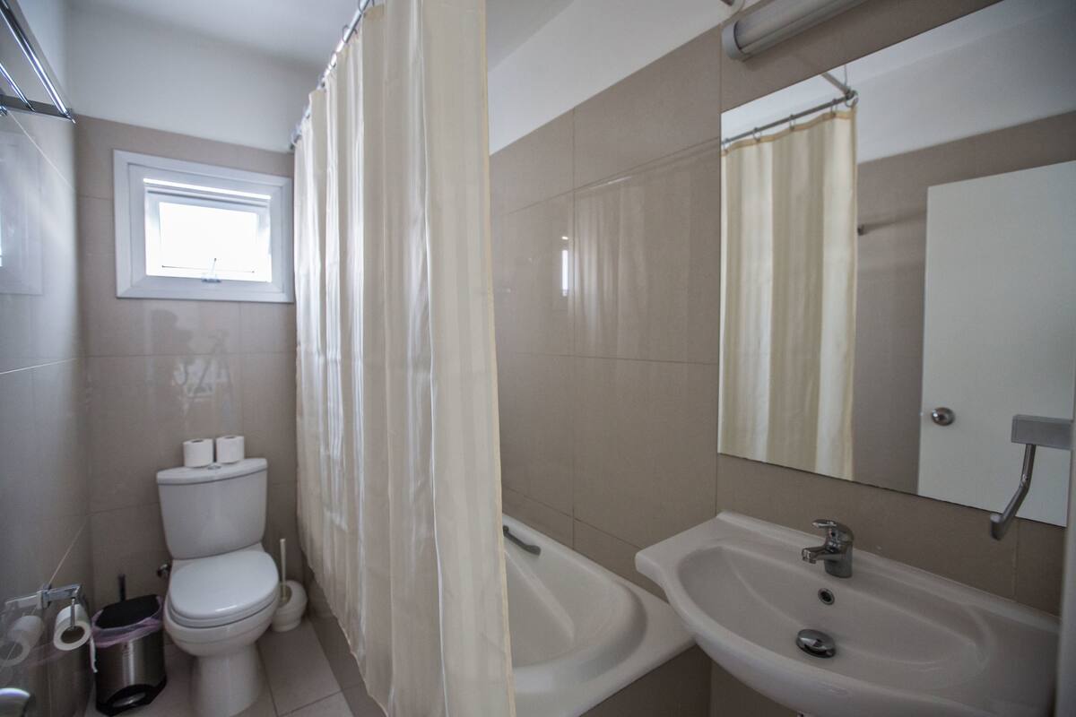 A bathroom with a toilet, bidet, sink, and a window.