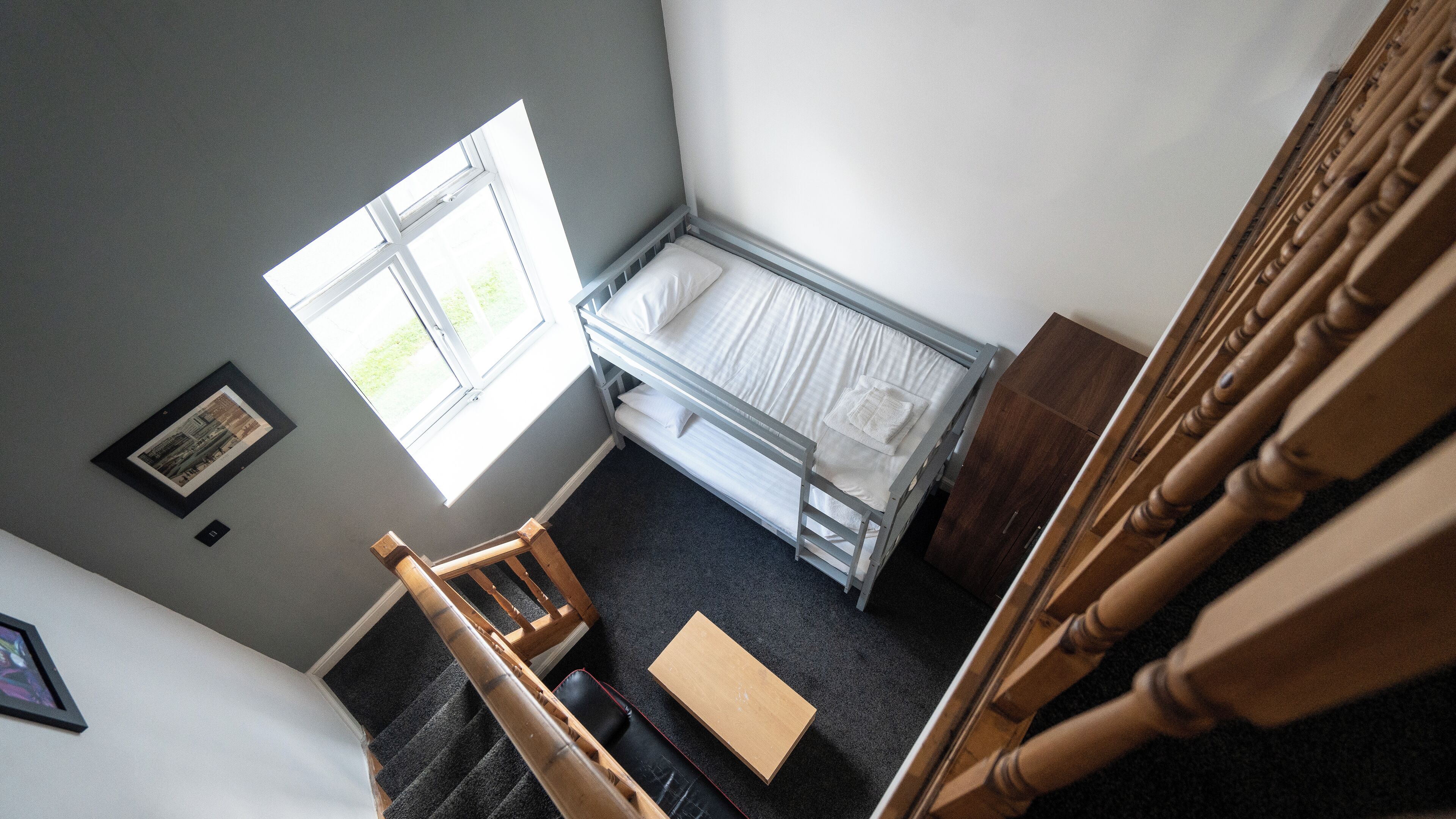Ein Schlafraum mit Etagenbett, kleinem Fenster und einer Treppe.
