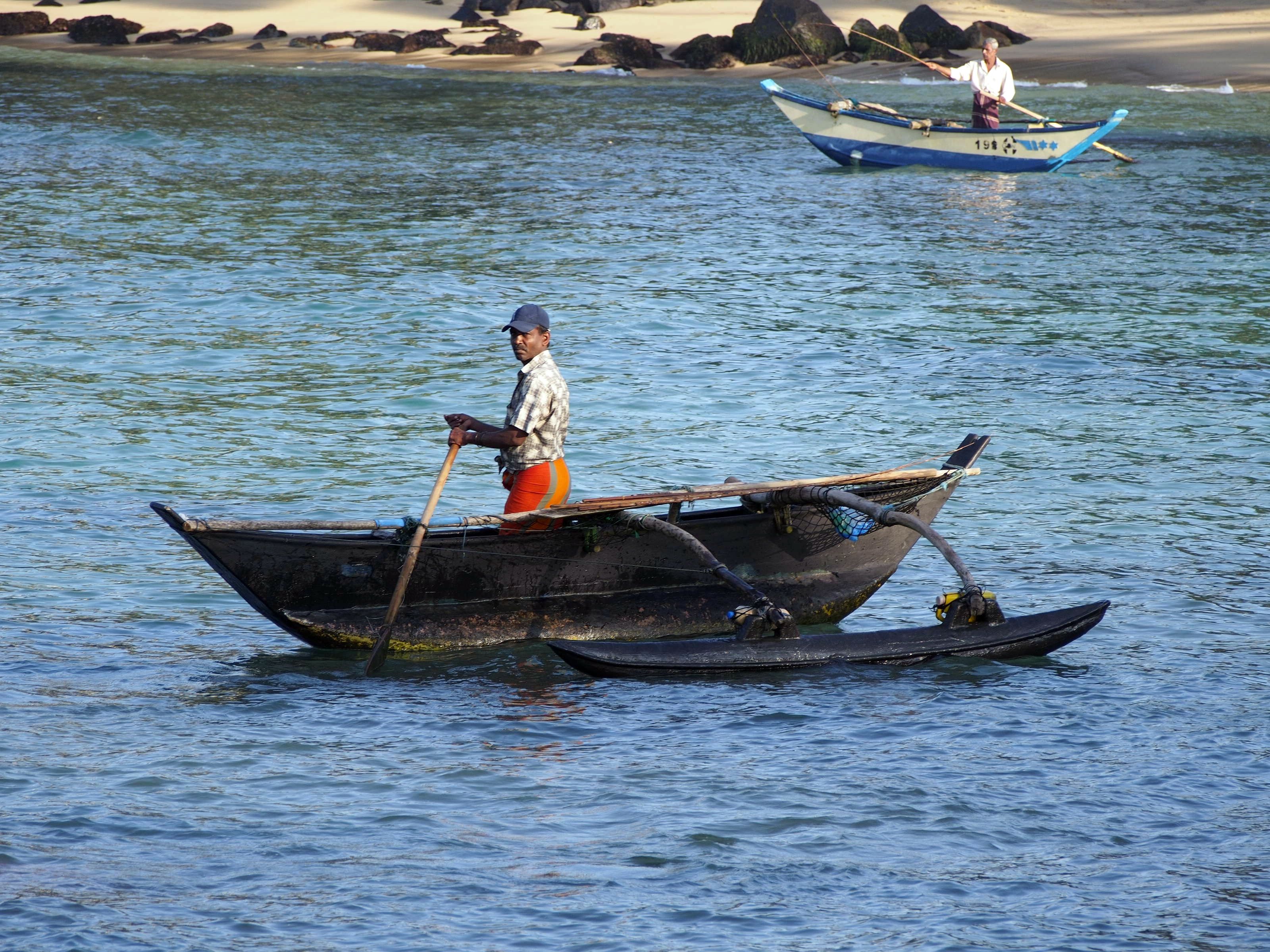 A man rowing a traditional boat on calm water.