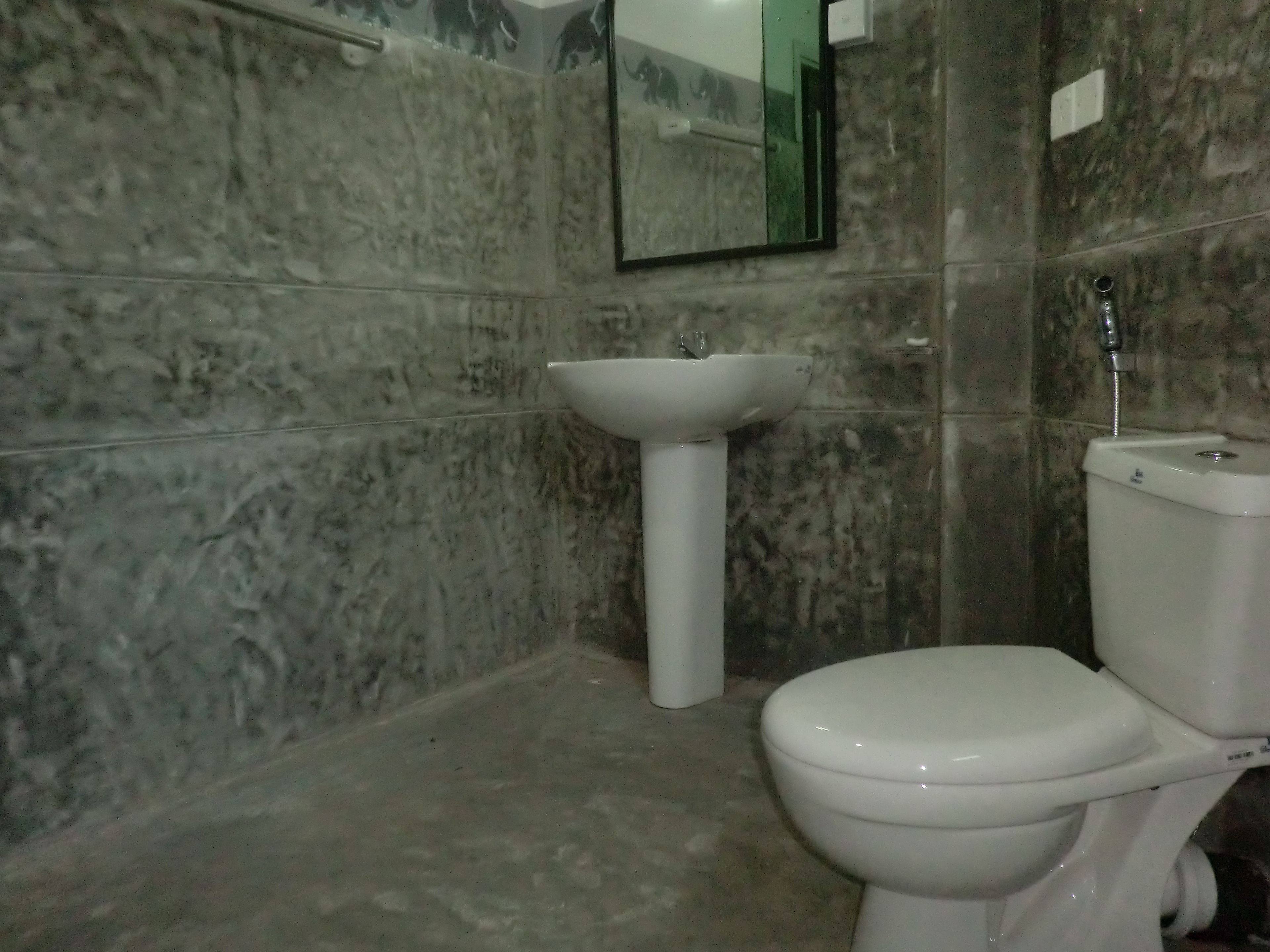 A bathroom with a toilet, sink, and mirror.