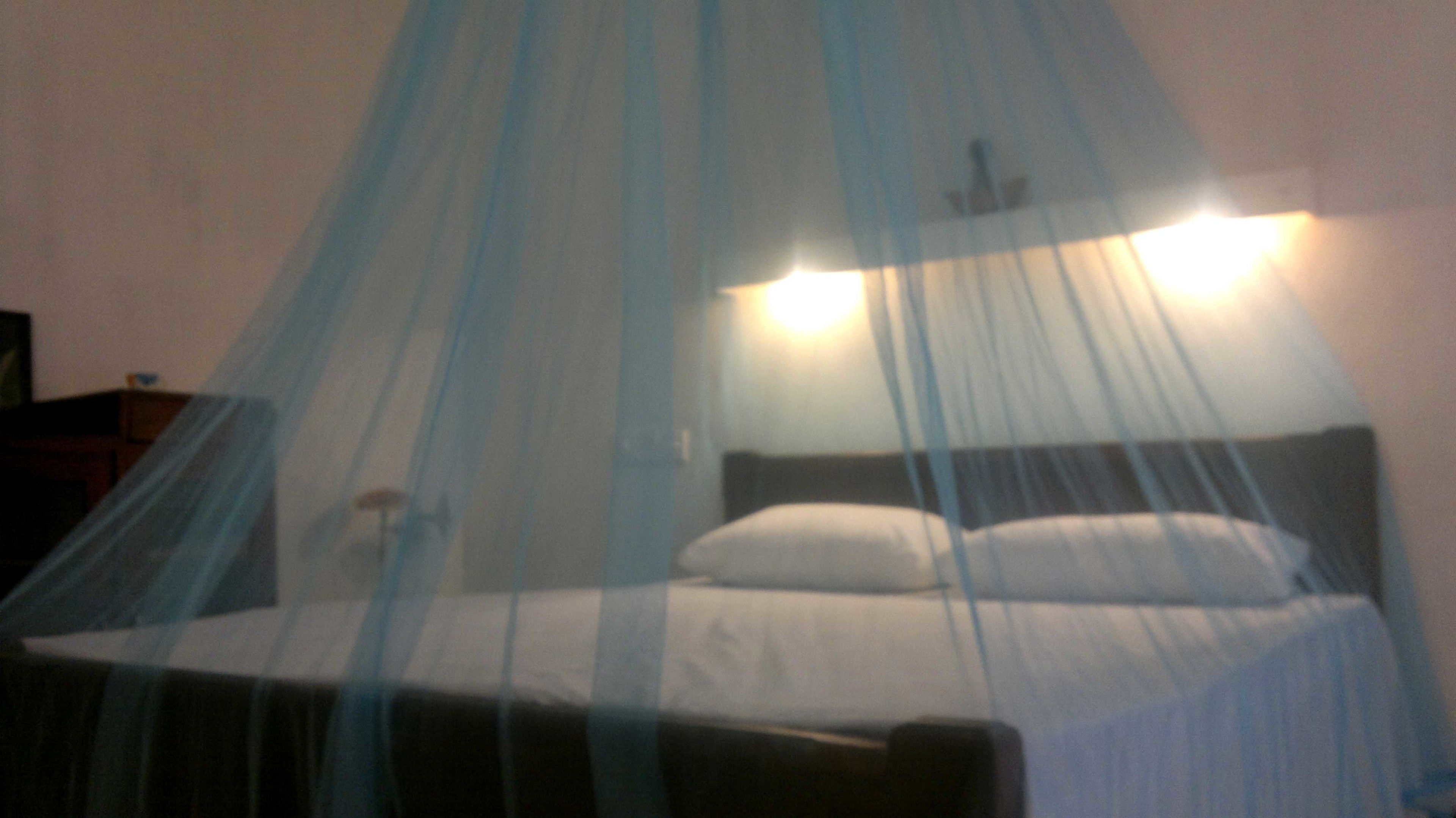 A bed with a headboard, a bedside table, and a wall-mounted light fixture.