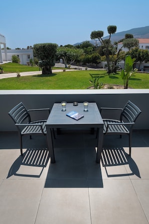 A patio with a table and chairs, a glass of water, and a book.