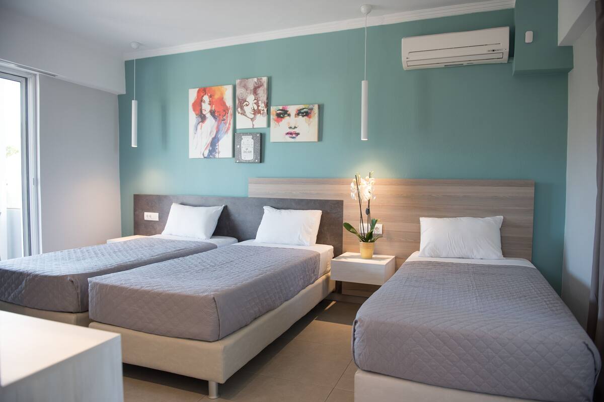 Ein Hotelzimmer mit zwei Betten, einem Nachttisch mit Lampe und Wandbildern.
