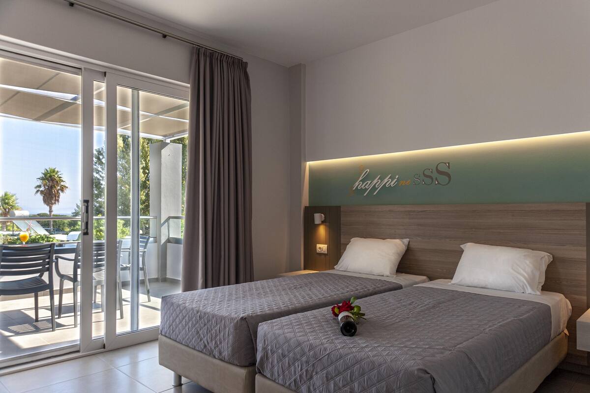 Ein Hotelzimmer mit zwei Betten, einer Glasschiebetür zu einem Balkon und einem Schild mit der Aufschrift 'happy SS'.