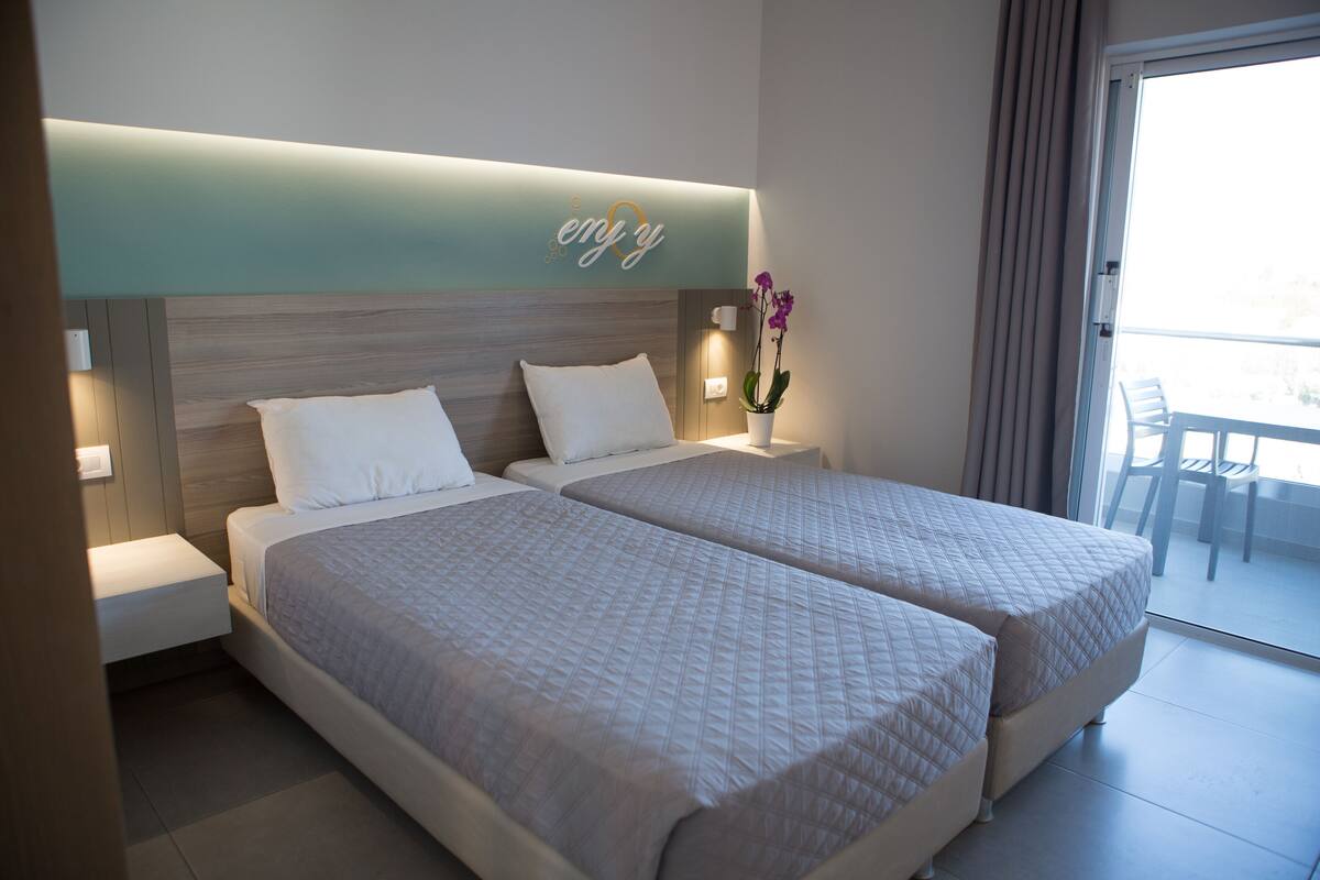 Ein Hotelzimmer mit zwei Betten, einem Nachttisch, einer Wandleuchte und einem Blumentopf.