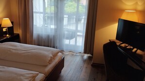 Une chambre d’hôtel avec deux lits, une télévision et une fenêtre avec des rideaux.