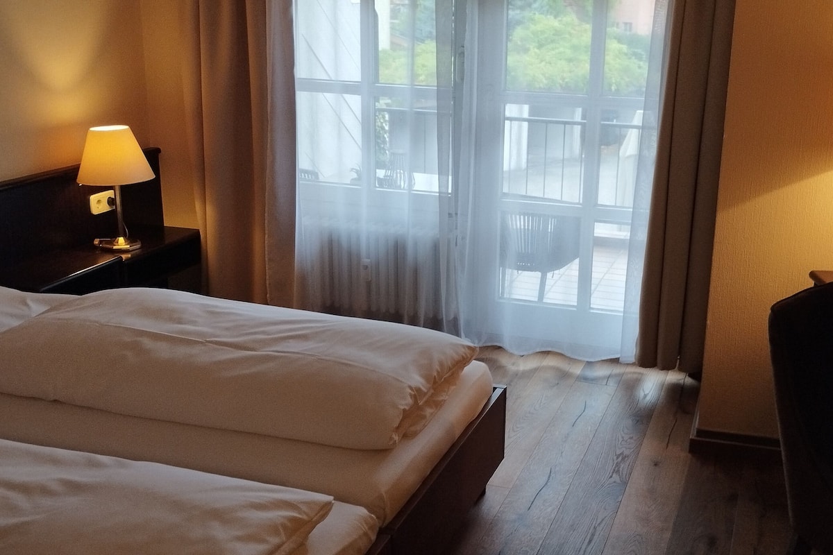 Une chambre d’hôtel avec deux lits, une télévision et une fenêtre avec des rideaux.