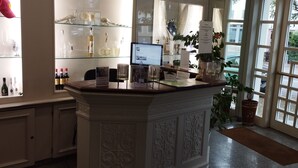 Un espace d’accueil avec une vitrine où sont exposées des bouteilles et un écran d’ordinateur.