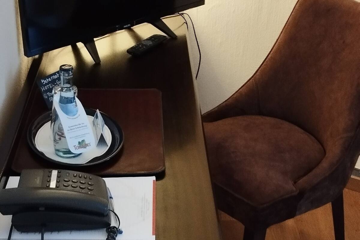 Un bureau avec un écran d’ordinateur, un téléphone et une télécommande.