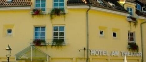 A yellow building with a sign reading "HOTEL AM THEATER".